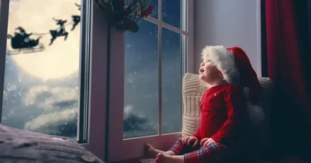 Child in Santa hat looking out window at Santa's sleigh flying across the moon on Christmas night